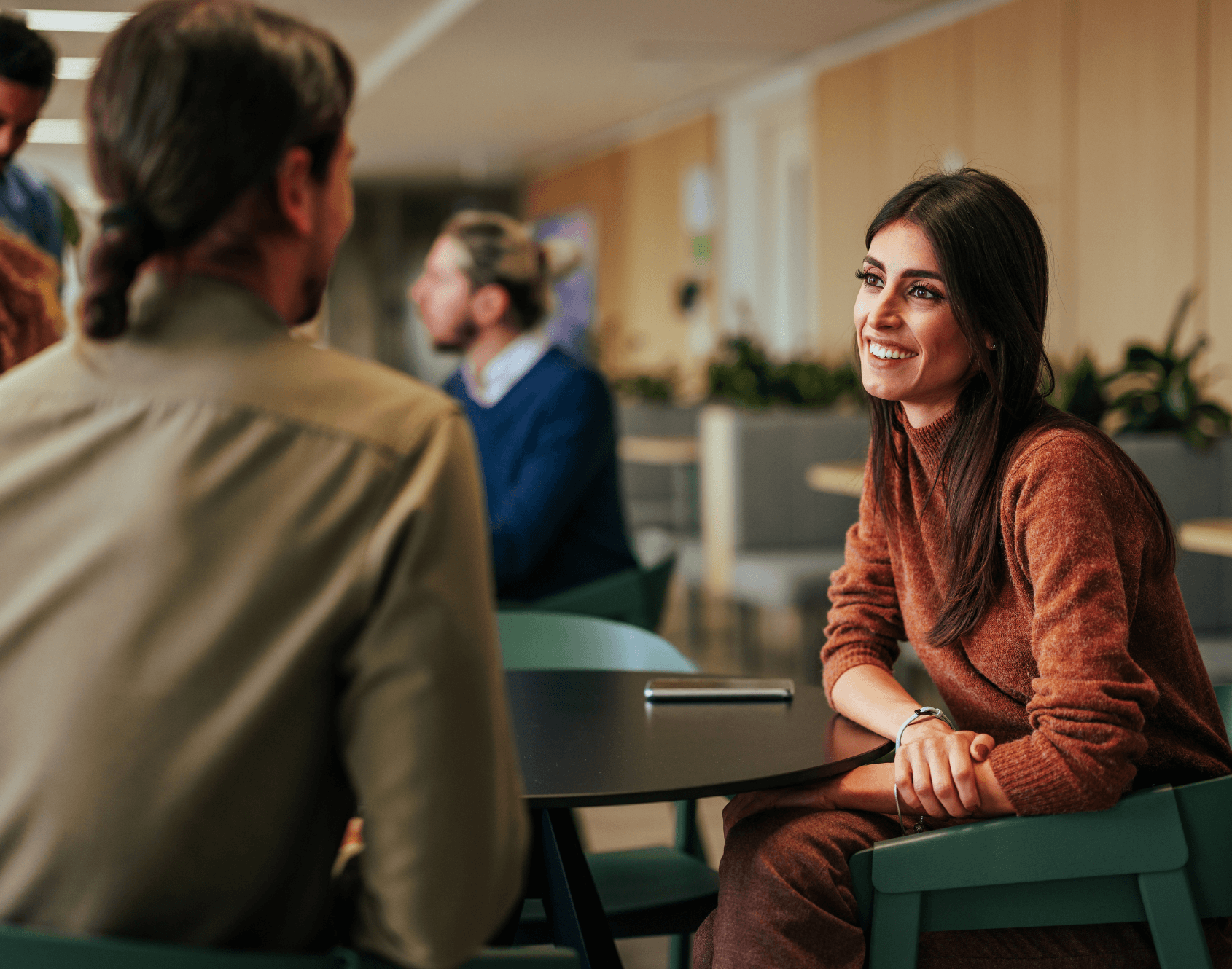 Two colleagues engaged in conversation while seated in an office environment.
