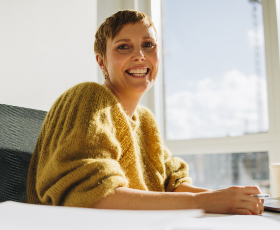 A professional smiling while seated in an office environment.