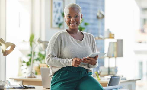 A professional smiling while seated in an office environment.