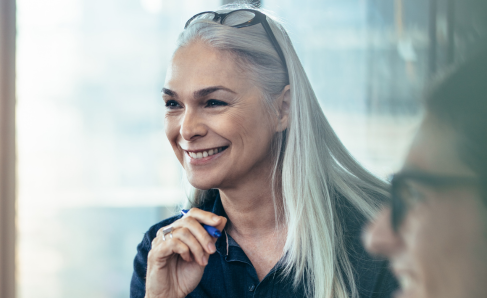 A professional smiling while seated at a work desk.