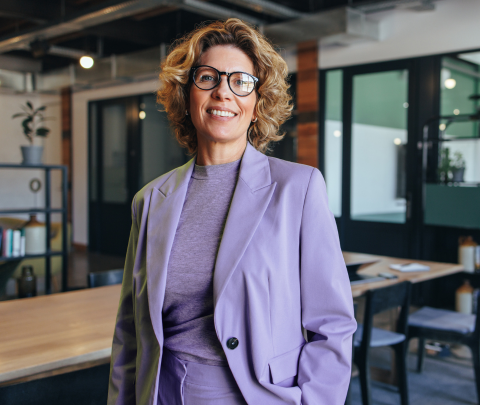 A professional smiling while stood in an office environment.