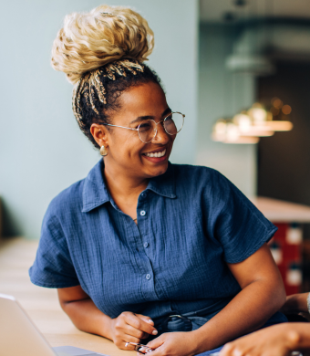 A professional smiling while seated in an office environment.