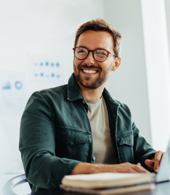 A professional smiling while seated at a work desk.