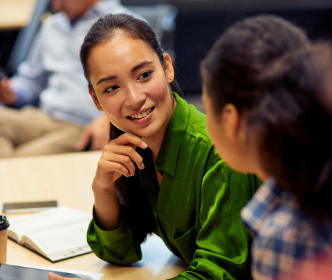 Two colleagues engaged in conversation while seated in an office environment.