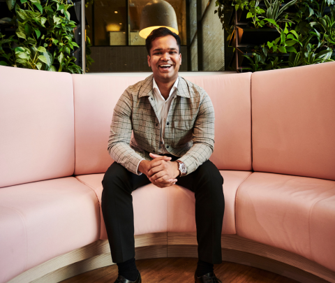 A professional smiling while seated in an office environment.