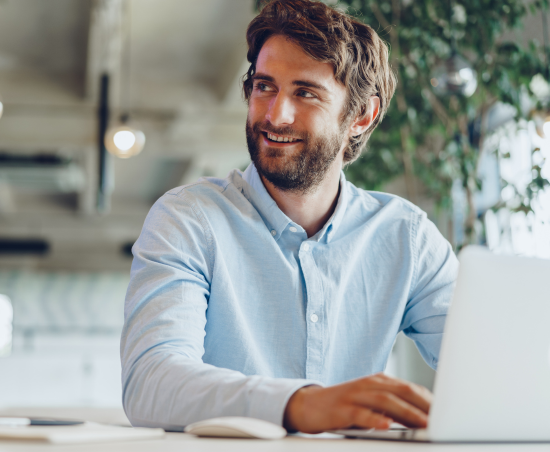 A professional smiling while seated at a work desk.