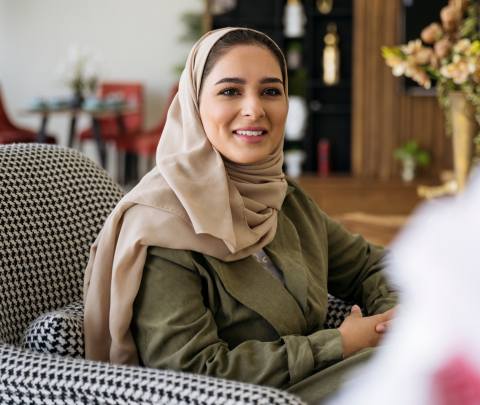 A professional smiling while seated at a work desk.