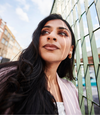 A professional seated outside of the office, looking up.