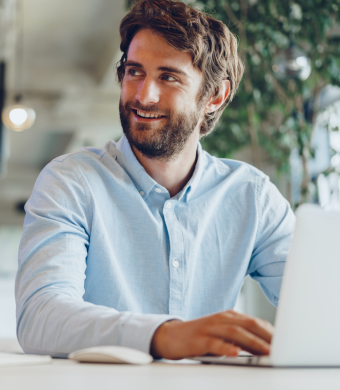 A professional smiling while seated in an office environment.