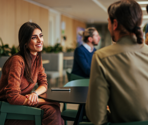 Two professionals engaged in a conversation in an office environment.