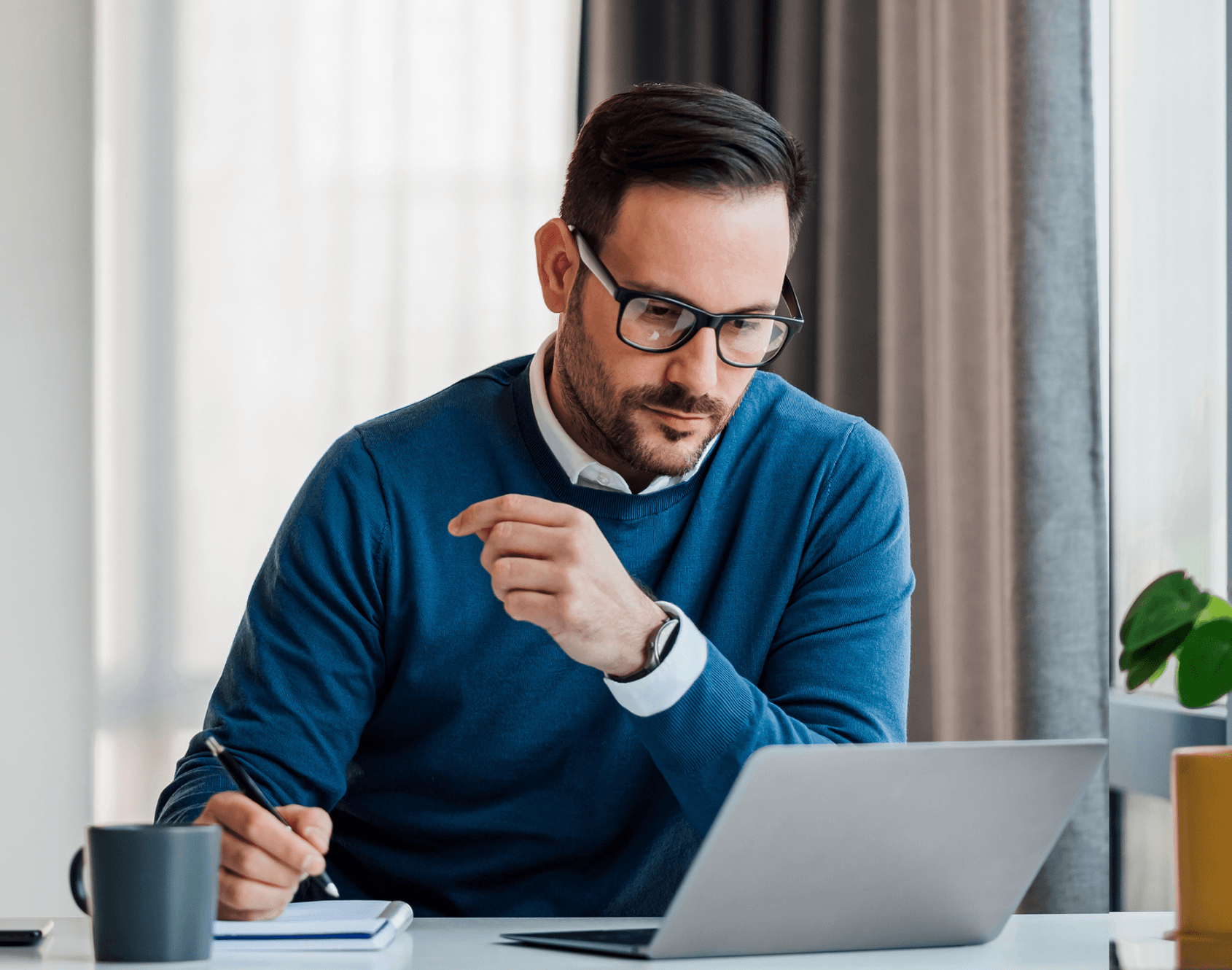 A professional sat in an office and working on a laptop.