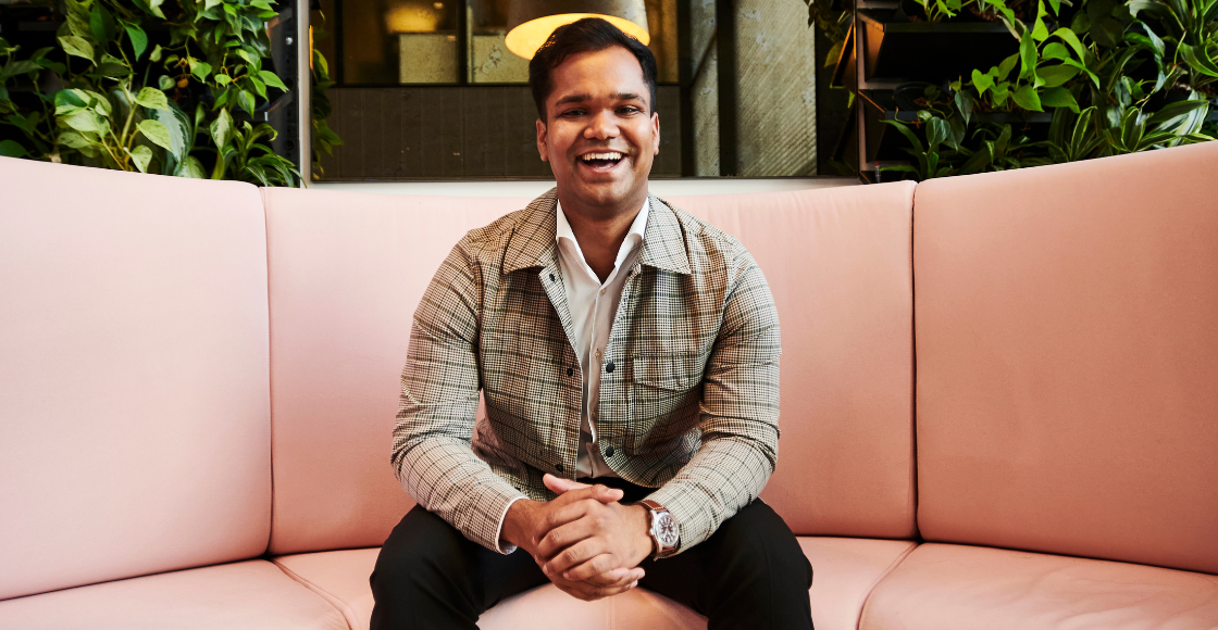 A professional smiling while seated in an office environment.