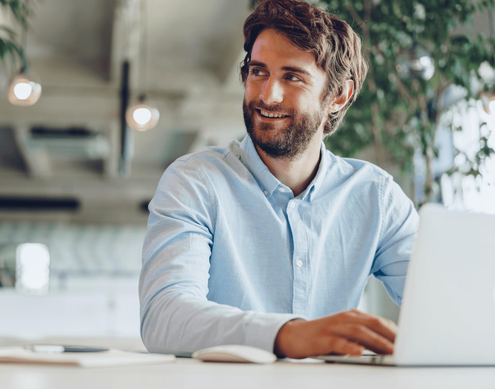 A professional smiling while seated at a work desk.