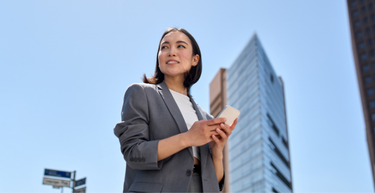 A professional walking outside of the office, looking towards the sky.