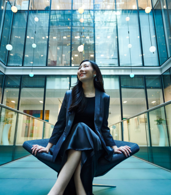 A professional seated outside of the office, looking up.