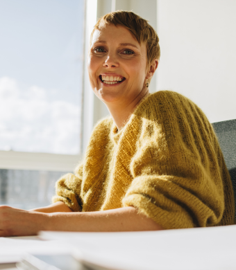A professional smiling while seated at a work desk.