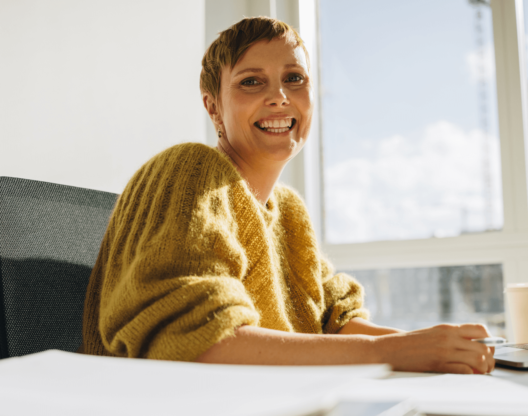 A professional smiling while seated in an office environment.