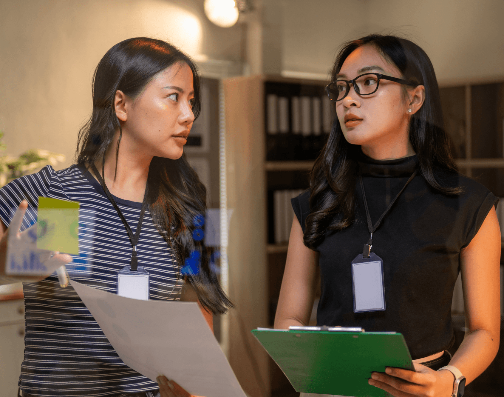 Two professionals engaged in a conversation in an office environment.