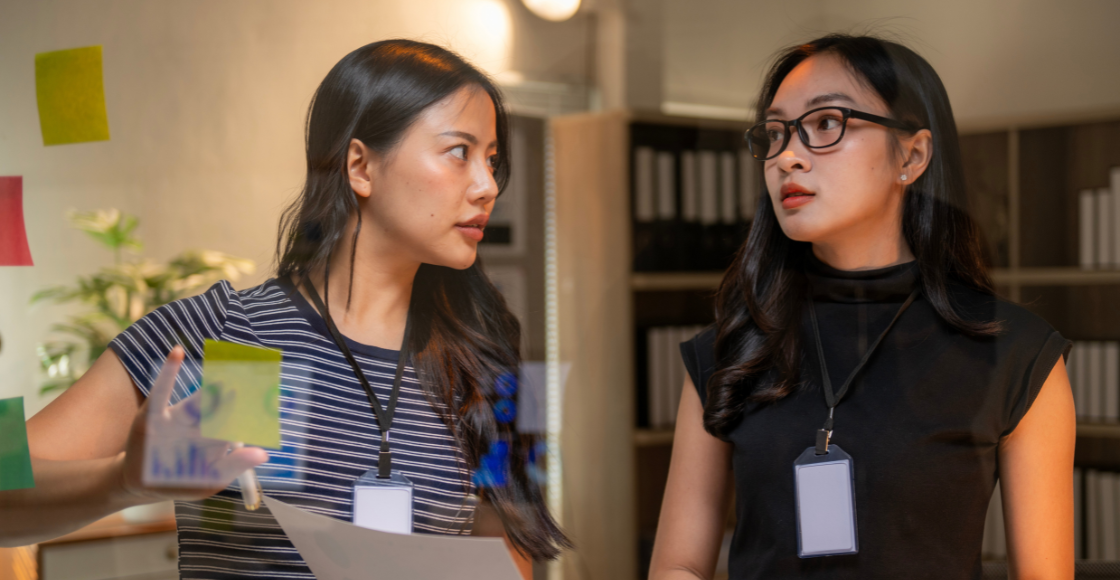Two professionals engaged in a conversation in an office environment.
