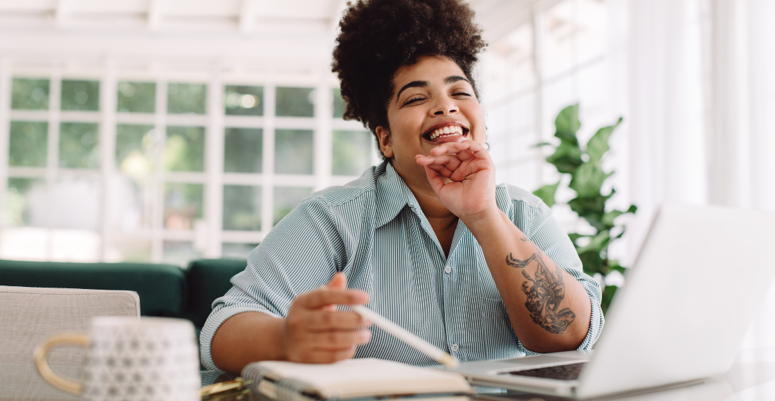 A professional smiling while seated in an office environment.