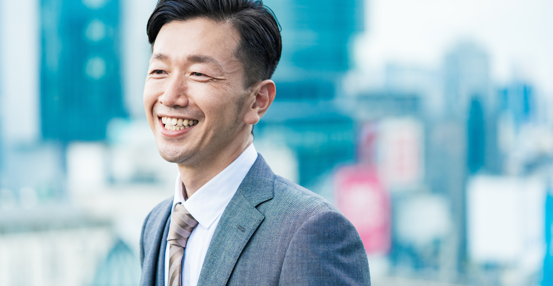 A professional smiling outside of the office.