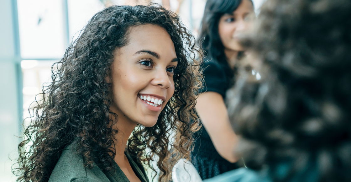 Two colleagues engaged in conversation while seated in an office environment.