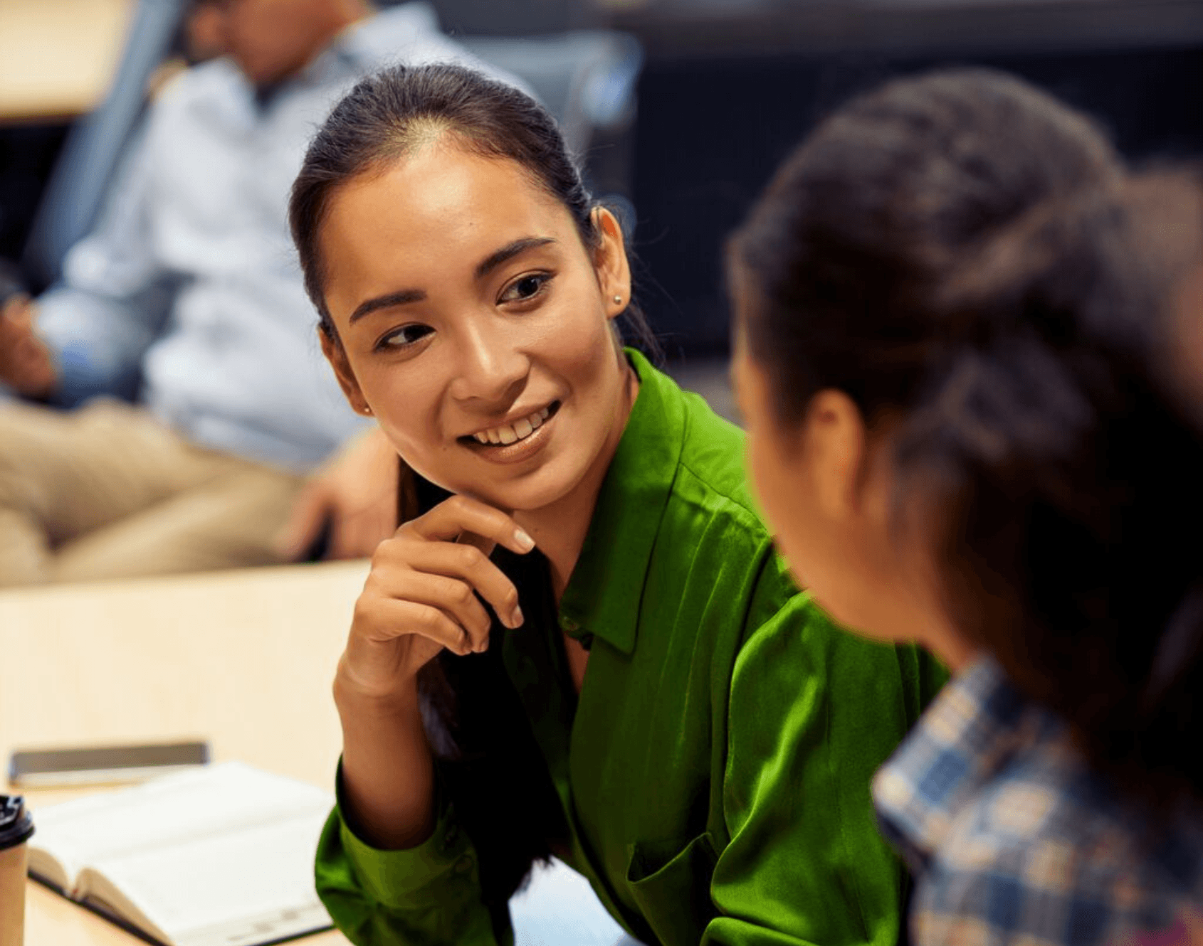 Two colleagues engaged in conversation while seated in an office environment.