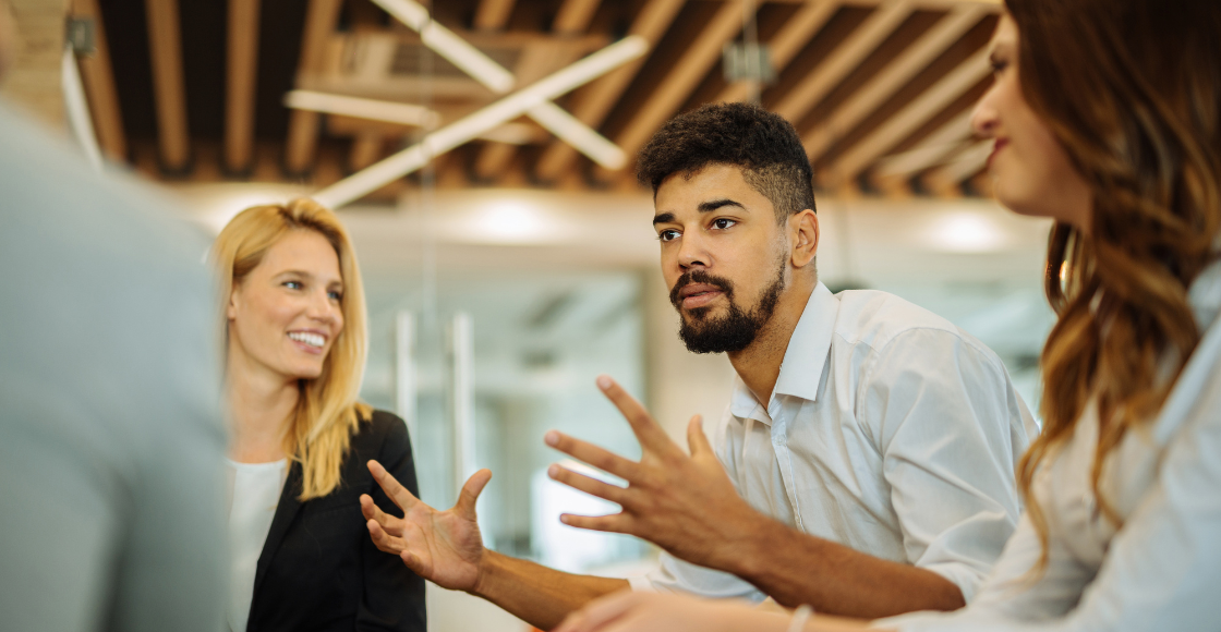 A group of professionals seated in a modern office space, engaged in conversation.