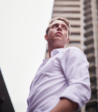 A professional standing outside of the office, looking up.