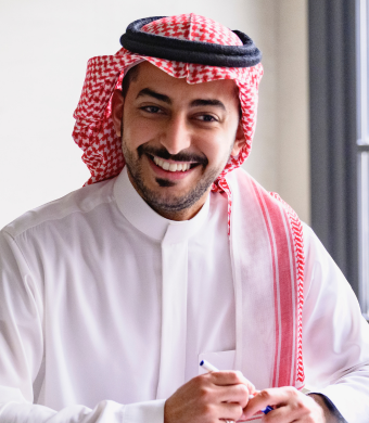 A professional smiling while seated at a work desk.