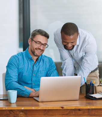 Two colleagues engaged in conversation while seated in an office environment.