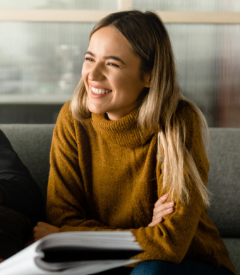 A professional smiling while seated at a work desk.
