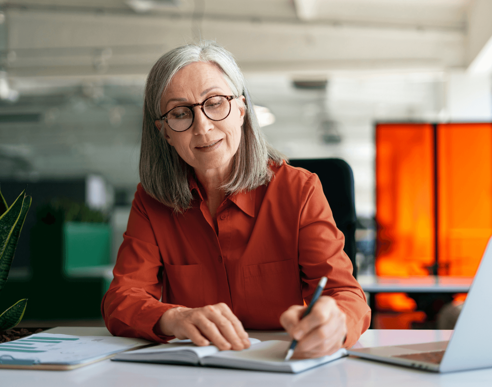 A professional smiling while seated at a work desk.