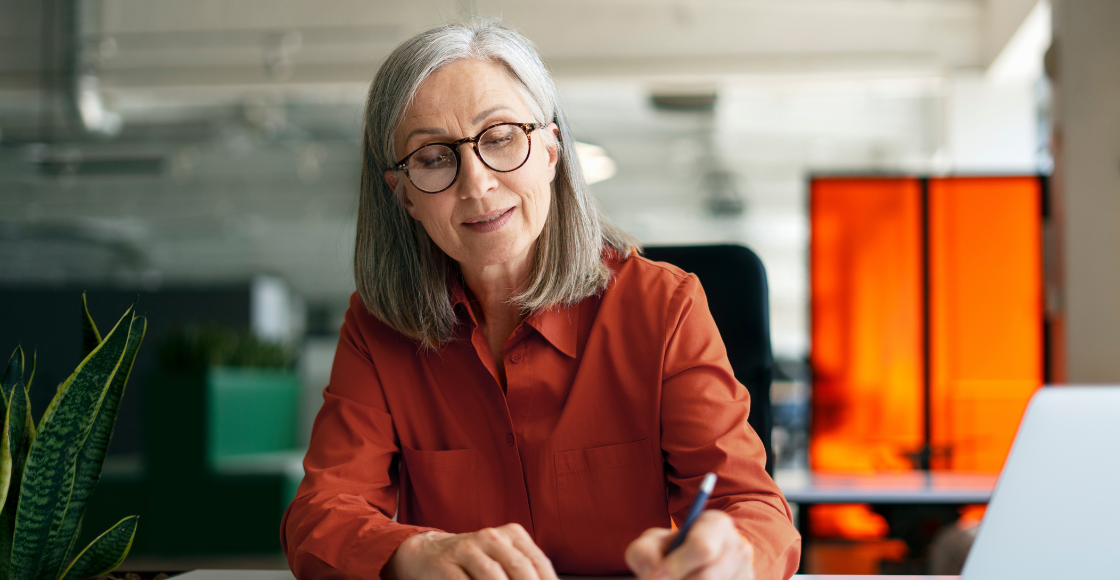 A professional smiling while seated at a work desk.