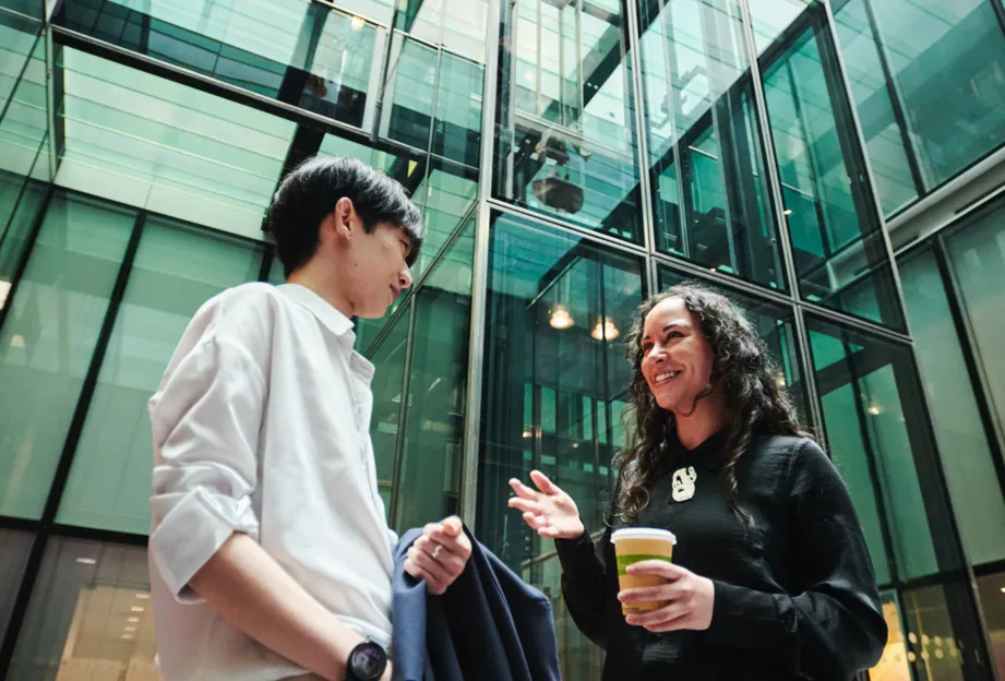Two young colleagues with coffee talking outside the office
