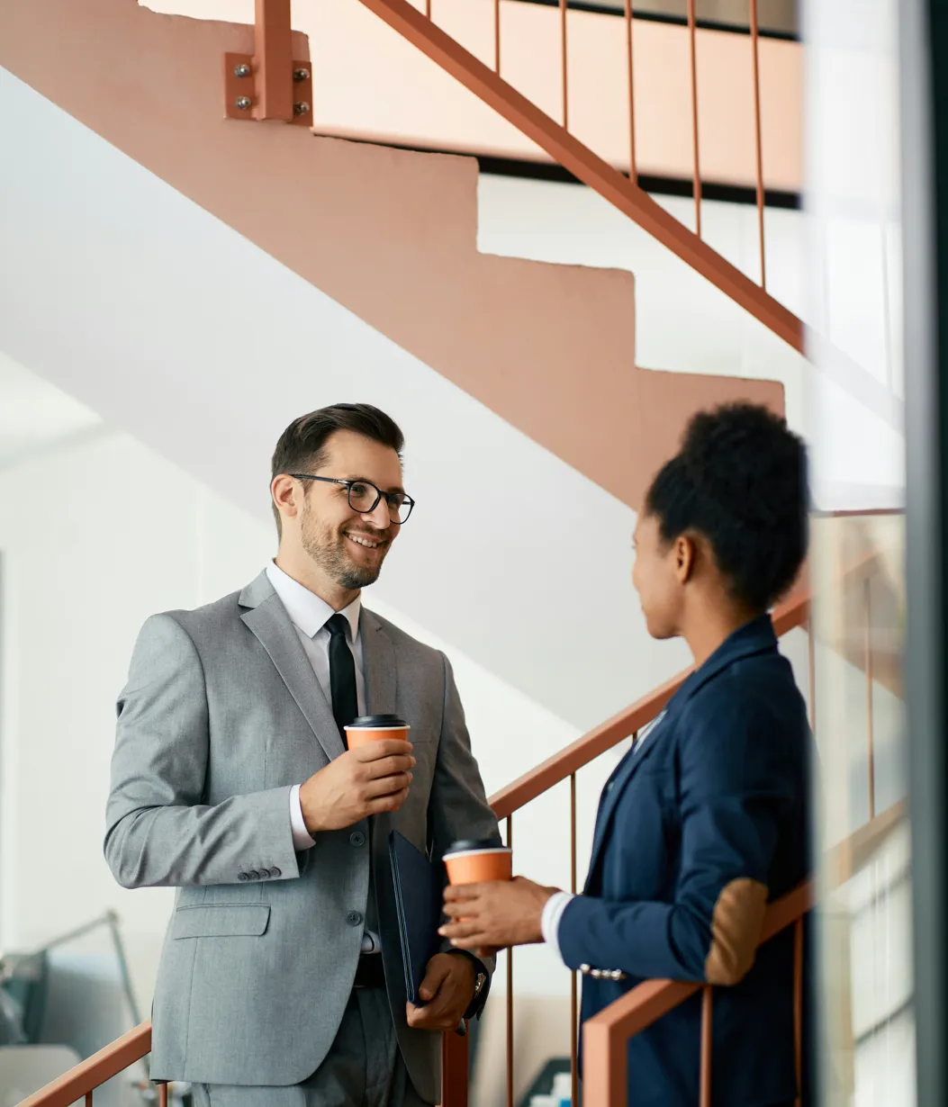 Two colleagues in formal wear talking in stairwell of office