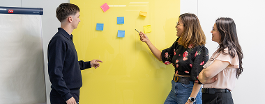 Groupe collaborant devant un mur de pense-bêtes