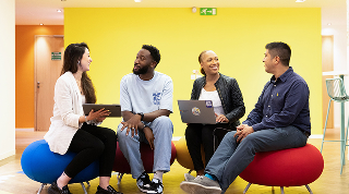 Quatre collègues souriants en discussion dans un espace coloré