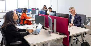 Cinq personnes travaillent à des bureaux dans un bureau moderne à aire ouverte