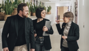 Trois collègues échangent dans un couloir de bureau