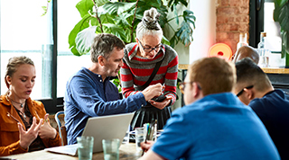 Groupe au bureau, regardant un téléphone