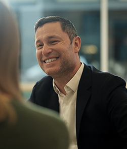 Person in business attire smiling during conversation indoors