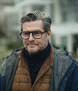 Portrait of person with glasses wearing layered jacket outdoors