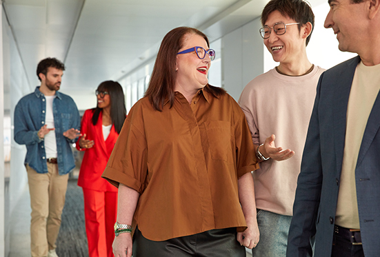 Group of coworkers walking and talking in office hallway