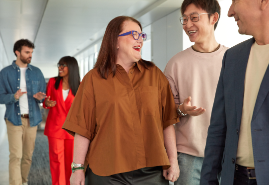 Group of coworkers walking and talking in office hallway