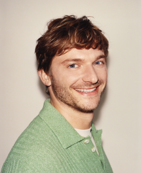 Person in green shirt smiling against plain background
