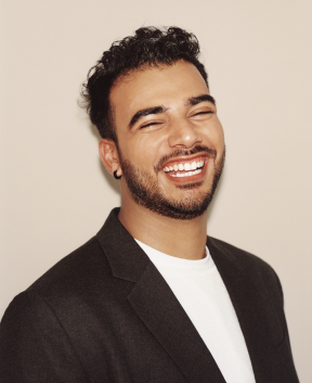 Person smiling in black blazer against plain background