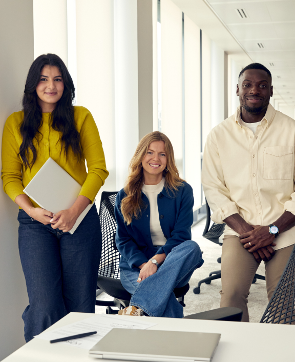Three coworkers posing bright office hallway area,