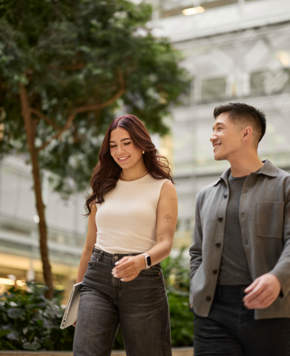 Two people walking outdoors chatting beside trees