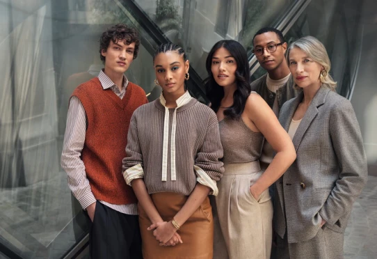 Five people pose in modern glass building interior